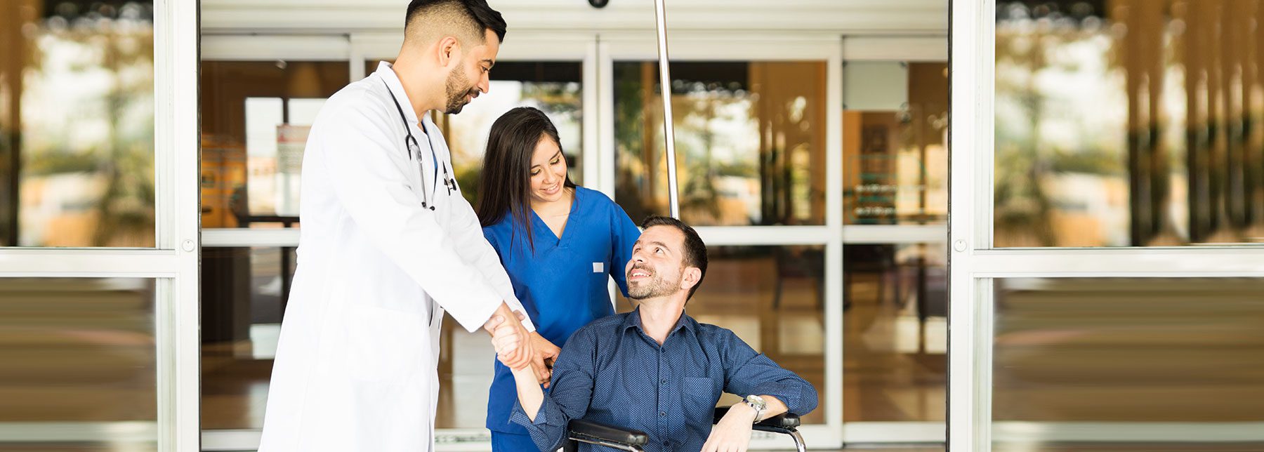 car accident victim leaves the hospital in a wheelchair with a nurse and doctor
