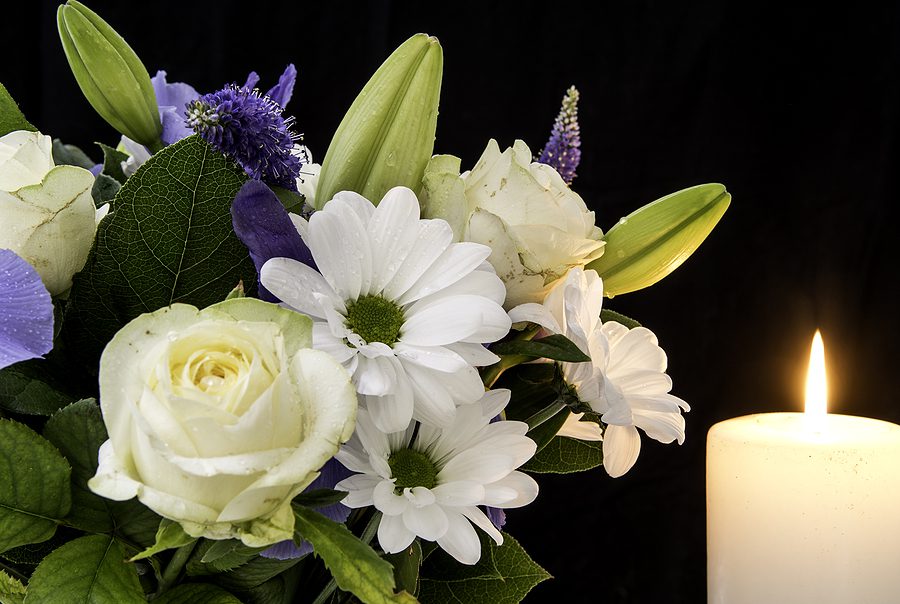 Funeral Bouquet purple White flowers and burning white candle. Speak with an expereinced Maumee Wrongful dealth attorney