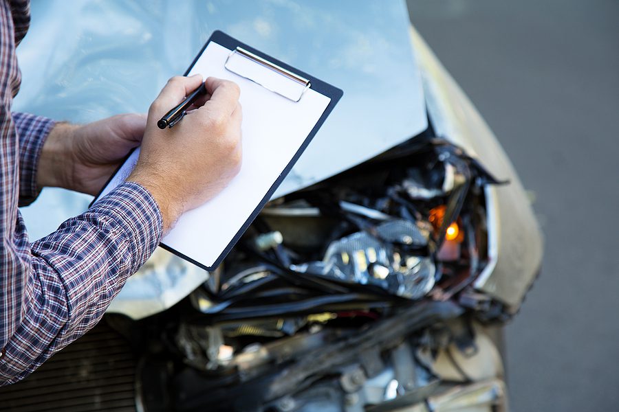 Male hands with clip board writing on paper at the site of a car accident - If you've been injured in an accident that wasn't your fault in Whitehouse, Ohio, contact Arthur Law Firm