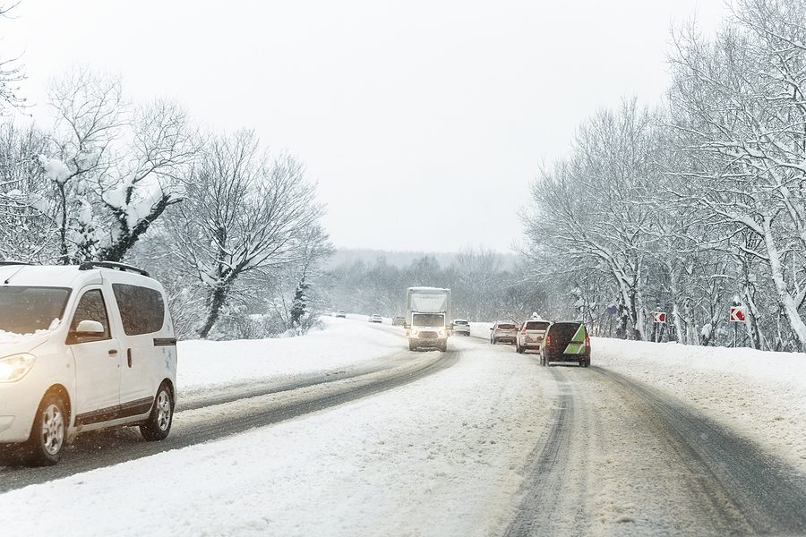 Curved road covered in snow with cars driving on each side