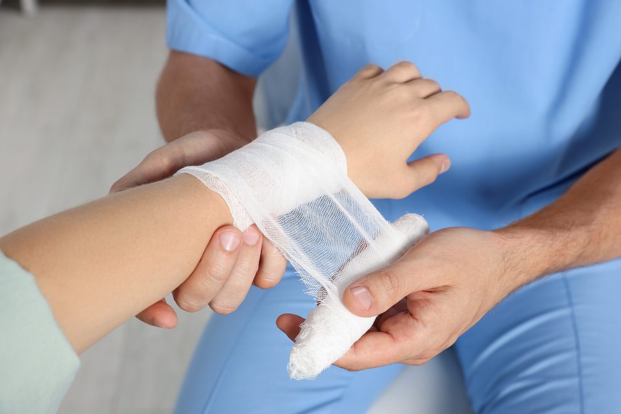 Doctor or nurse bandaging a persons wrist.