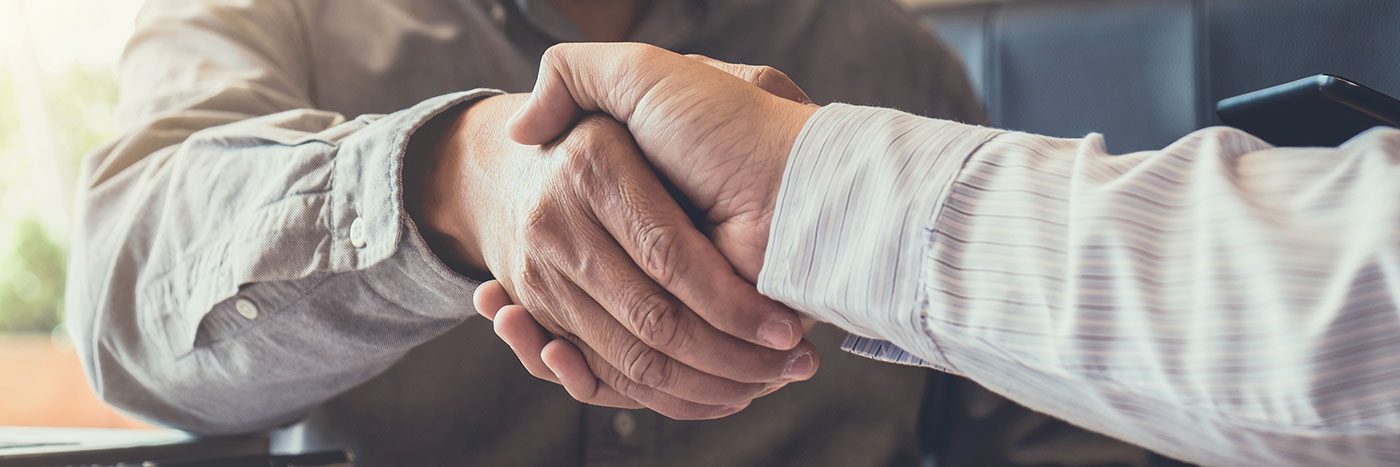 close up photo of two mens arms shaking hands