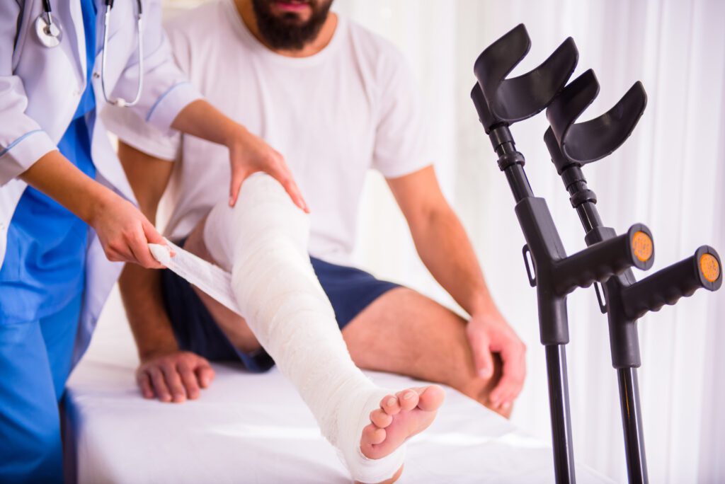 Injury leg. Young man with injured leg. Young woman doctor helps the patient. If you've been injured in an accident that wasn't your fault in Holland, Ohio, contact Arthur Law Firm