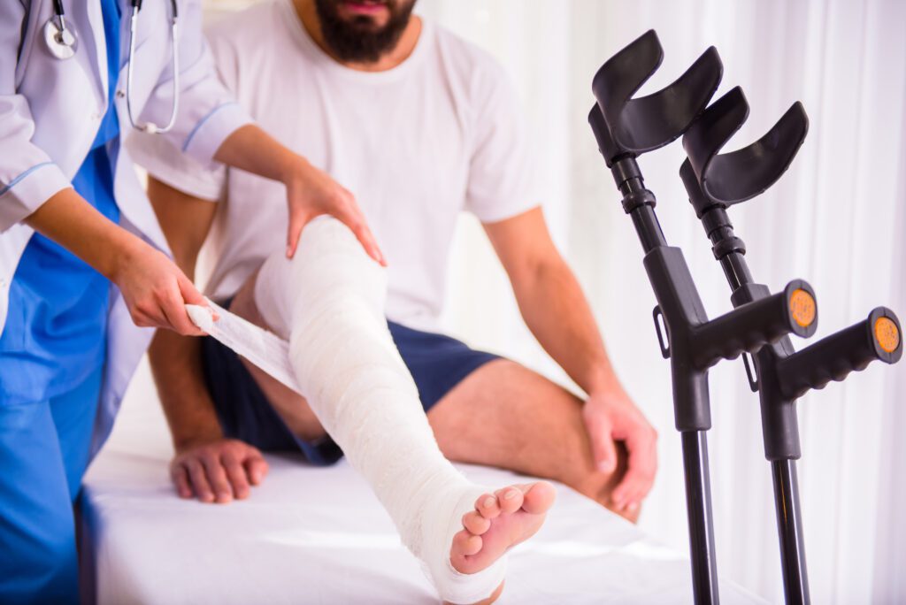 Young man with injured leg - Young woman doctor helps the patient wrap the leg in a cast. If you've been injured in an accident that wasn't your fault in Swanton, Ohio, contact Arthur Law Firm. 