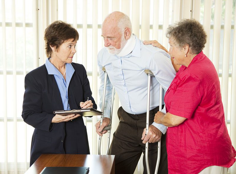 Injured elderly man on crutches and his wife meet with female lawyer in Maumee, Ohio about personal injury lawsuit.