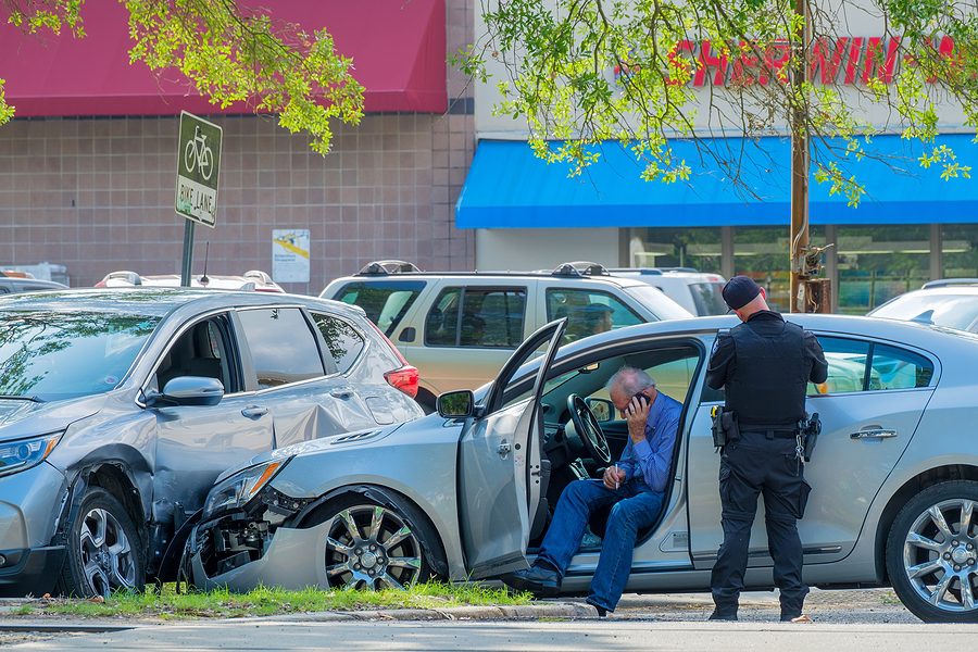 Car accident victim sitting in car talking on cell phone.