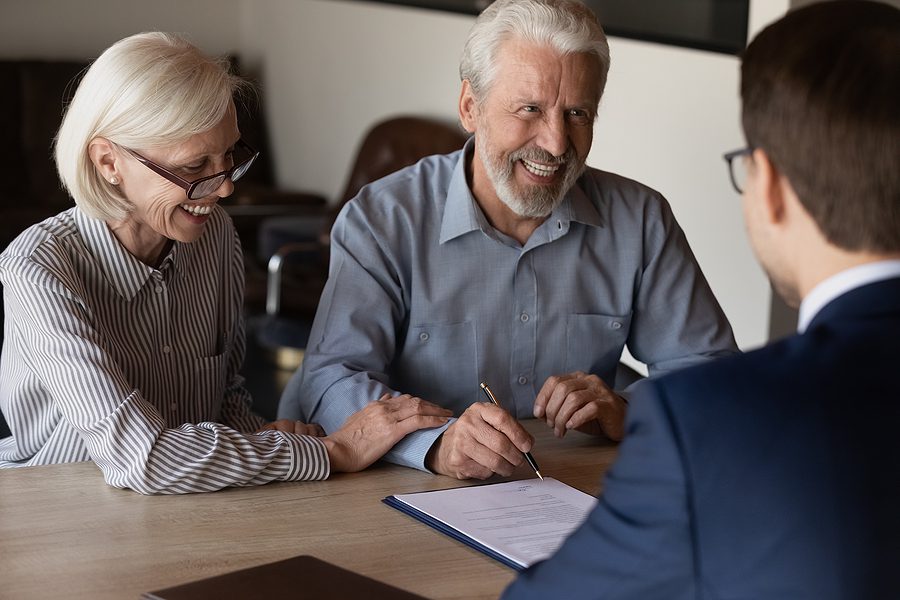 Mature couple smiling while meeting with a lawyer 