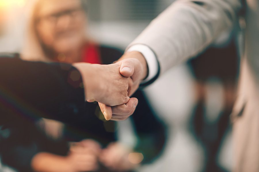 Close up photo of a handshake taking place - sunset glare on photo