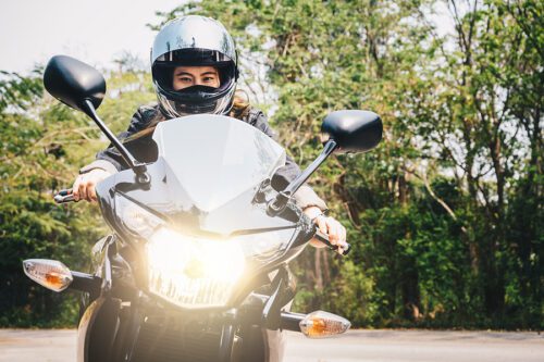 person on a motorcycle wearing a helmet, facing the camera with the headlight on. Toledo motorcycle attorney can help you if you are hit by a car and injured while riding your motorcycle.