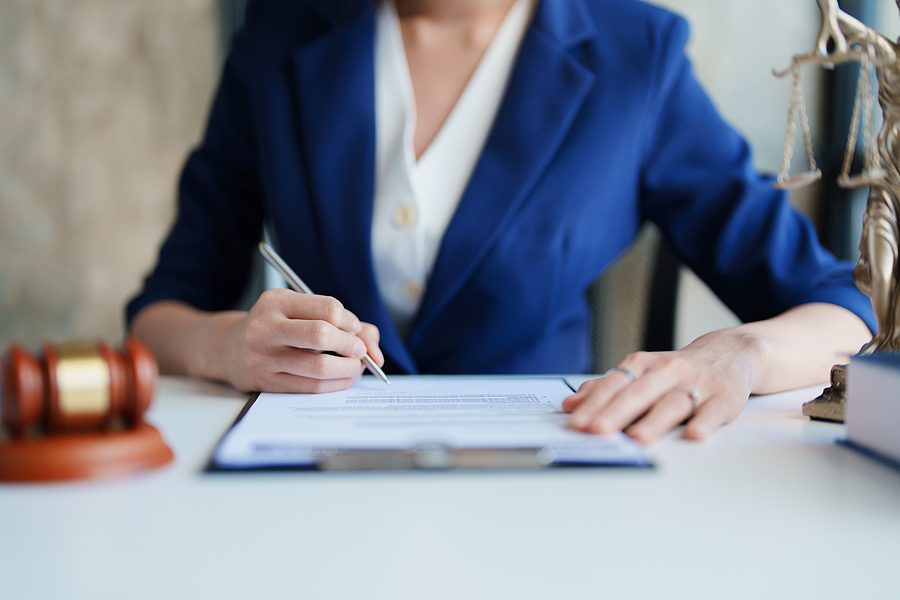 law consultation, woman sitting at a desk signing papers