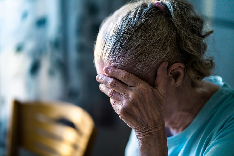 sad senior woman holding her head in her hand