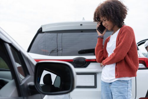 woman standing next to car after an accident talking to a bowling green, ohio lawyer on the phone