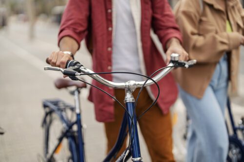 Hands pushing bicycle on a street. Close up of hands holding handlebars.