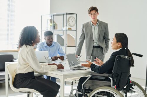 Business people talking to their business leader in wheelchair during business meeting at office