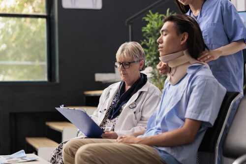 Assistant and physician helping asian patient to take off neck collar while in recovery after injury accident. 