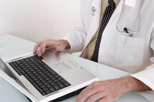close-up of doctor in a white cot working on a notebook computer