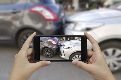 Close up hand holding smartphone and take photo at The scene of a car crash and accident.