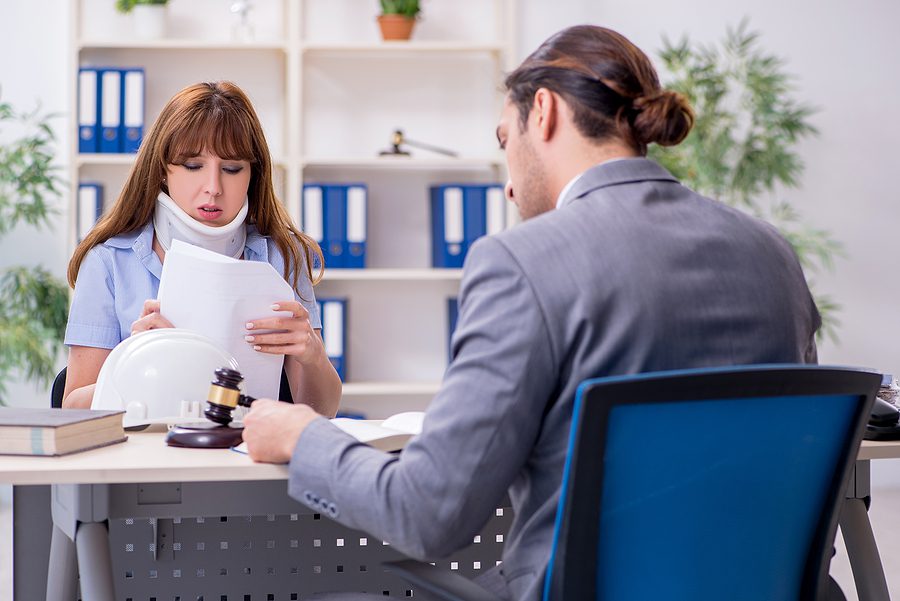 Young woman in a neck brace consulting with lawyer after a serious accident