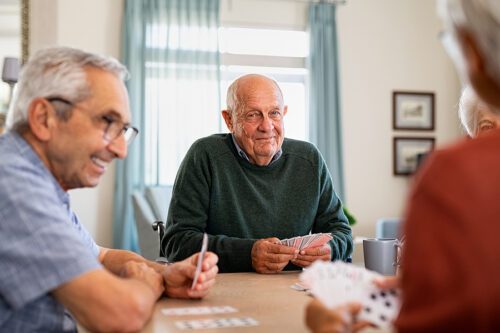 Retired senior man in wheelchair playing cards with friends