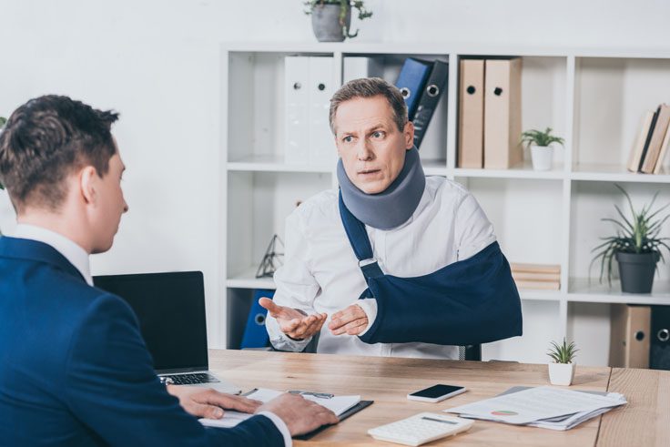 Middle Aged man in neck brace and arm slingspeaking with a lawyer after a motorcycle accident in grand Rapids Ohio