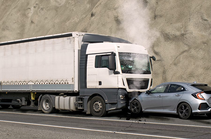 Accident between a semi-truck and a small silver sedan. 