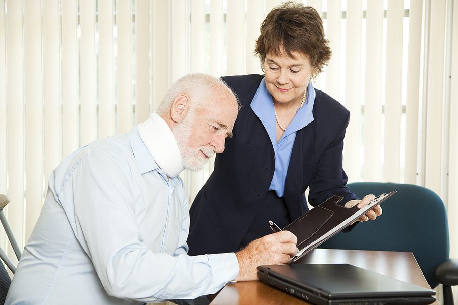 Older man signing paperwork with a female attorney. 