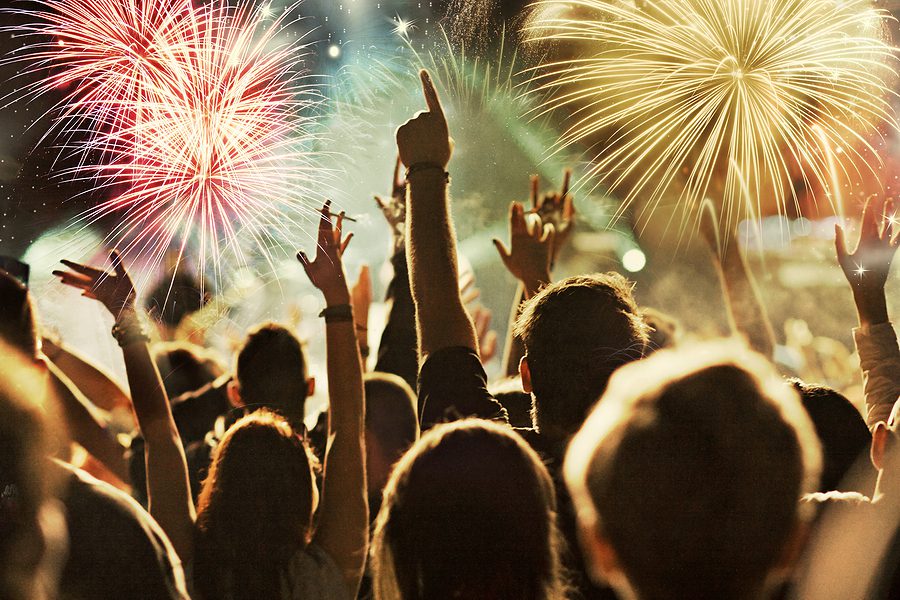 A large crowd of people watching fireworks at a summer event. 