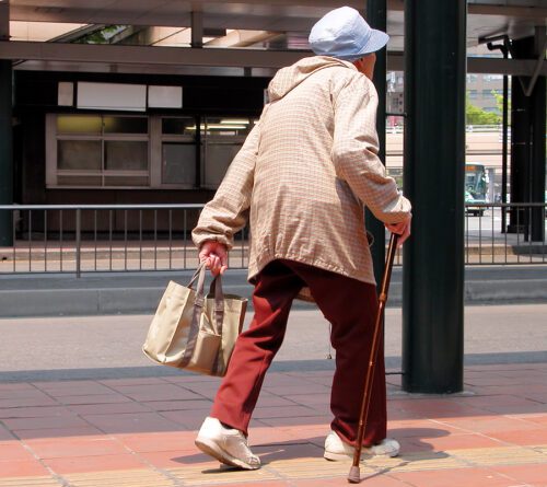 An old woman with bag walking in a bus station.