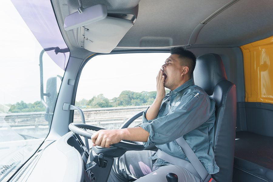 Professional truck driver behind the wheel yawning. 