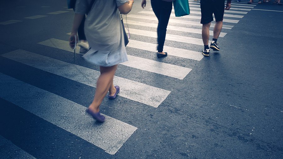 Feet of the pedestrians crossing on city street. 