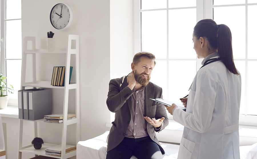 Male patient talking to a female physician about neck pain. 