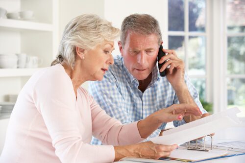 Older couple looking at bills or paperwork and looking stressed.