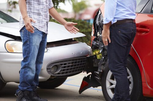 Two male drivers involved in a car accident, arguing over who is at fault.