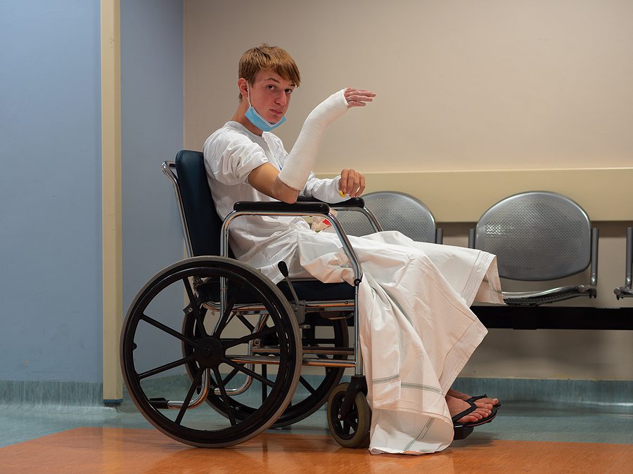 Young man sitting in a wheelchair in a hospital with multiple injuries from an accident. 