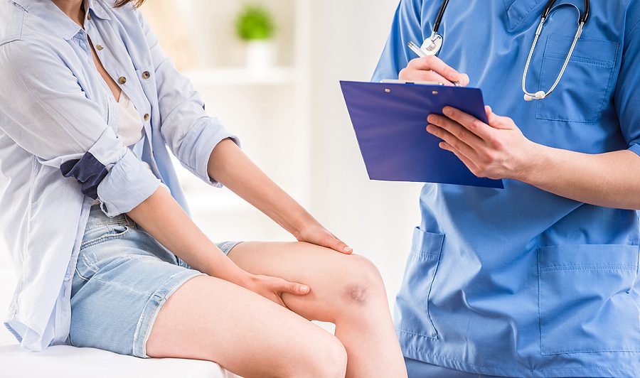 Closeup of a female at a doctor's office, talking to a doctor about her injuries. 