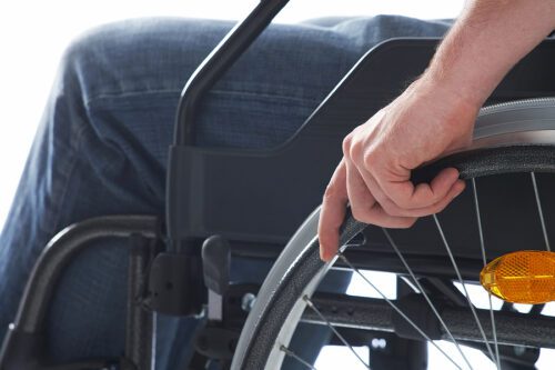 Closeup of a man sitting in a wheelchair with his hand on the wheel. 