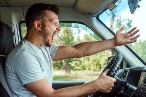 Angry, aggressive male driver yelling at the car in front of him. 