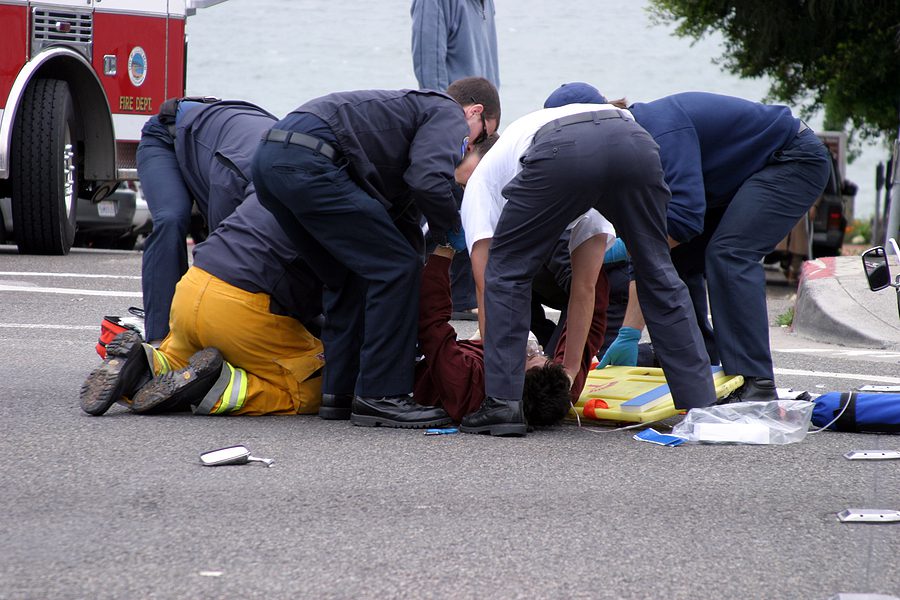 Paramedics helping a motorcycle victim who is lying injured on the road. 