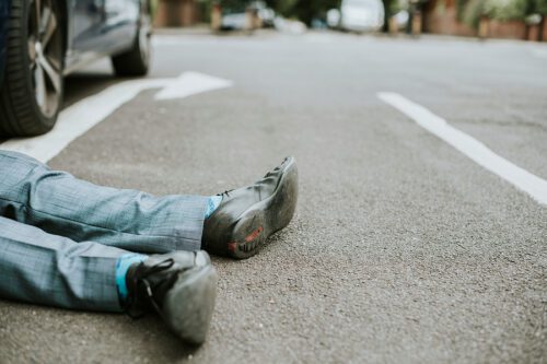 Closeup of a man's feet and lower legs on the street after he was hit by a car.