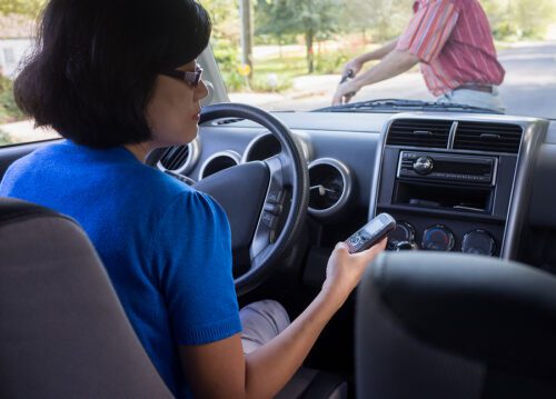 Woman driving and staring down at her phone about to hit a pedestrian.