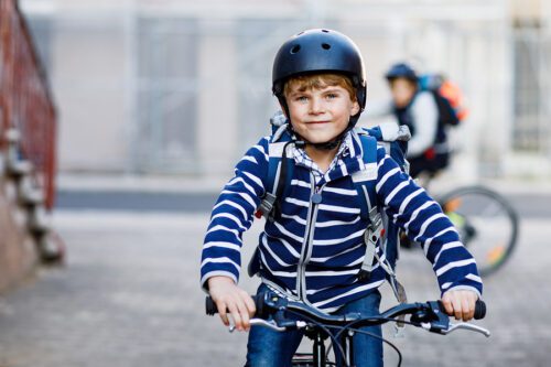 Closeup of a boy on a bike, wearing a blue helmet. 