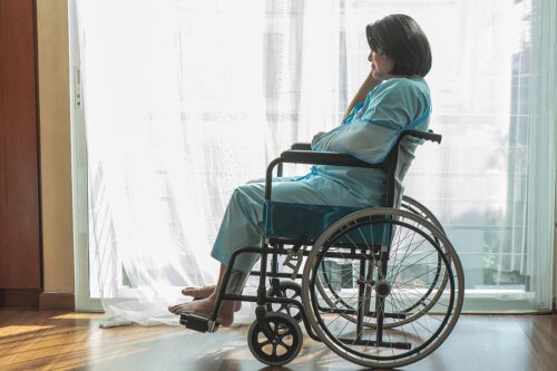 Injured woman sitting in a wheelchair staring out the window. 