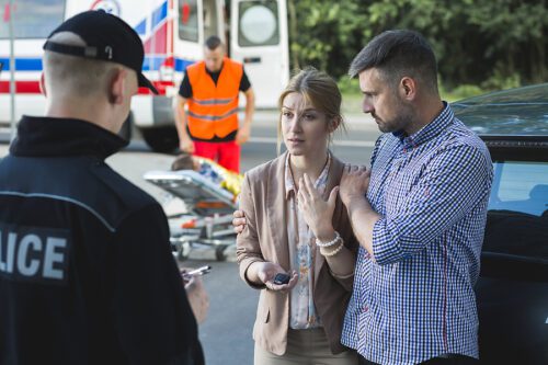 Man and woman who witnessed an accident, giving their statement to a police officer at the scene. 