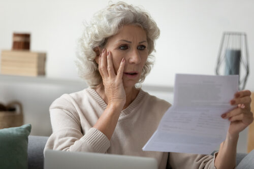 Senior woman reading her mail and looking disappointed and shocked. 