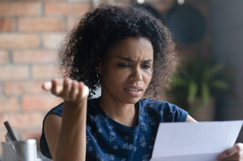 Woman reading a letter and looking confused and upset. 