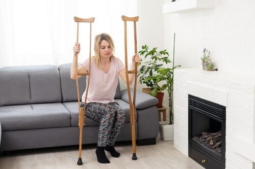 Injured woman sitting on her couch holding crutches. 
