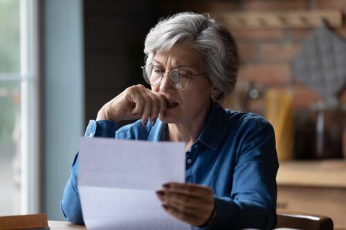 Older woman reading a letter and looking stressed. 