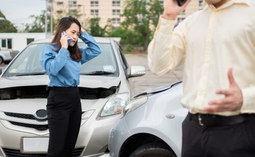 Two drivers call insurance after a car accident before taking pictures and sending insurance. Online car accident insurance claim idea after submitting photos and evidence to an insurance company.