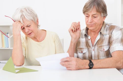 Senior couple reading a denial letter and looking upset.