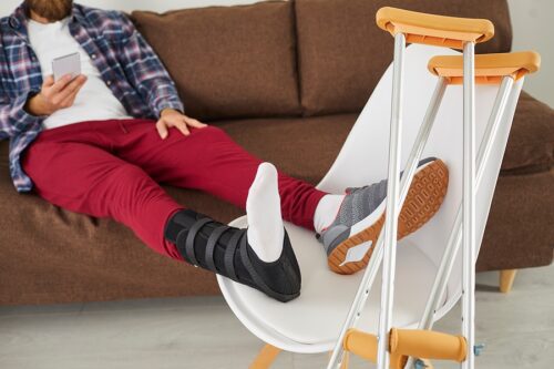 Injured man sitting on couch, ignoring incoming phone call.